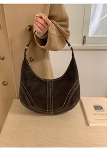 Close-up of vintage dark brown leather half-moon bag with elegant white contrast stitching