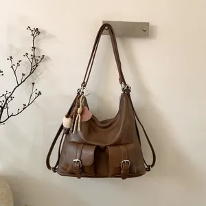 Detail view of a vintage dark brown tote bag featuring two buckled pockets and a heart charm