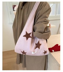 Detail view of pink plush star embroidered tote bag styled with a brown winter coat