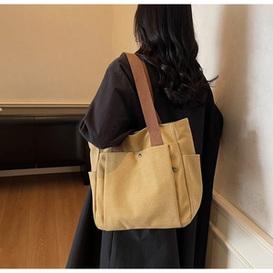 Détail du sac cabas en toile jaune avec bandoulière en tissu marron et poche latérale