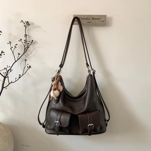 Close-up of brown leather tote bag with silver buckles and a cute plush charm