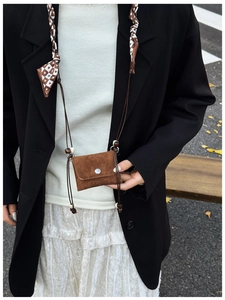 Brown suede mini crossbody bag with a plaid bow detail shown on a model outfit