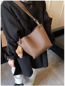 Détail d'un sac seau marron en cuir grainé avec un pendentif ours en peluche mignon