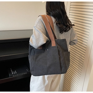 Grand fourre-tout noir en toile avec bandoulière marron porté par un mannequin chic