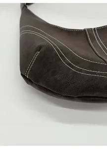 Detailed close-up of vintage brown leather underarm bag featuring contrast white stitching