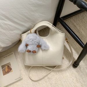 Detail of cream white leather bucket bag with vertical stitching and plush rabbit charm