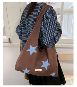Detail of brown star-embroidered plush tote bag with brand label and spacious interior