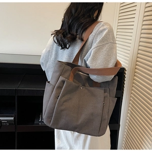 Vue détaillée du sac cabas en toile gris foncé avec poches et bandoulière marron