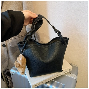 Détail macro du sac seau en cuir grainé noir avec surpiqûres blanches contrastées