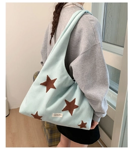 Detailed side view of large mint blue plush tote bag with brown star patches on model
