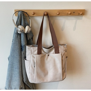 Détail du sac cabas en toile avec poche frontale à pression et anses marron robustes