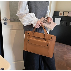 Detail of caramel brown faux leather tote bag with black button closures and front pocket