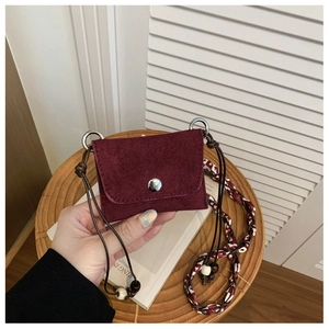 Close-up of a burgundy suede mini bag with unique scarf-braided strap and wood beads
