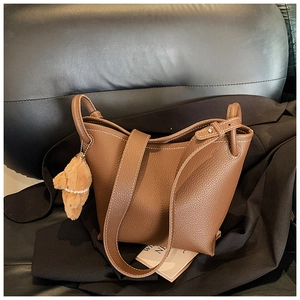 Détail du sac seau en cuir marron avec surpiqûres blanches et breloque ourson