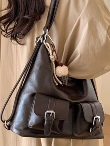 Vintage dark brown tote bag with side pockets and acorn charm on beige coat model