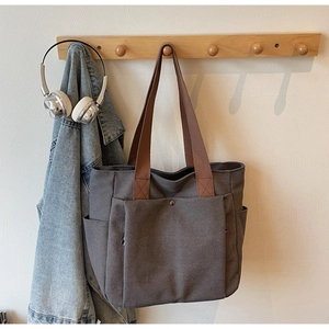 Détail d'un sac cabas en toile avec anses marron et poche frontale fonctionnelle