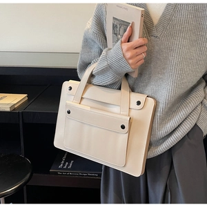 Detailed close-up of cream leather tote bag featuring a front pocket and contrast button