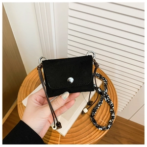 Detail of mini black matte crossbody bag featuring silk scarf and beaded strap accents