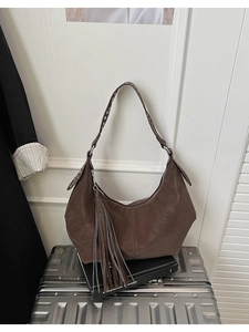 Detail of dark brown vintage underarm bag with long fringe tassel and matte leather texture