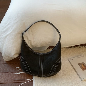 Detail of black leather hobo bag featuring contrast white stitching and metal buckle
