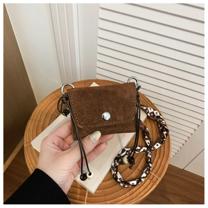 Detail of vintage brown suede mini bag with heart pattern scarf strap and metal snap