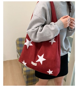 Detail of red star embroidered velvet tote bag showing large capacity on model