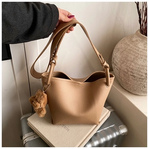 Détail du sac seau beige avec texture grainée et charmant porte-clés ours en peluche brun