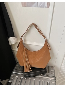 Detailed view of brown leather shoulder bag with silver studs and long leather tassel