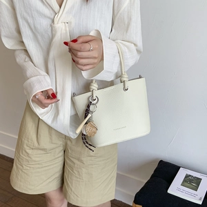 Beige lychee pattern bucket bag with creative pendant shown in a lifestyle scene