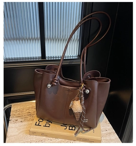 Detailed view of brown leather tote bag with knot handle and plush ice cream charm