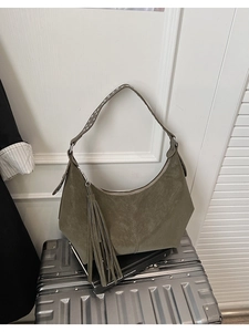 Detail of hobo shoulder bag featuring suede texture, tassel charm and studded strap