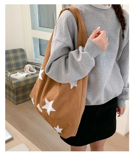 Brown suede tote bag with white star embroidery shown on model for daily outfit style