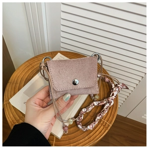 Detail of dusty pink suede mini crossbody bag featuring a decorative silk scarf on strap