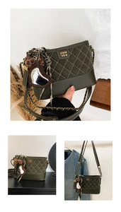 Detail of dark green quilted shoulder bag with metal logo, chain strap and heart charm