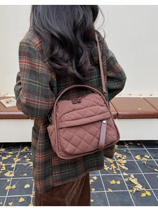 Donna che indossa una grande borsa a tracolla trapuntata marrone scuro in un parco