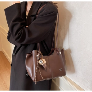 Detail of dark chocolate brown PU leather tote bag with metallic ball and knot shoulder strap