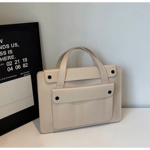 Detail of a beige tote bag showing its fine leather texture and front flap pocket design