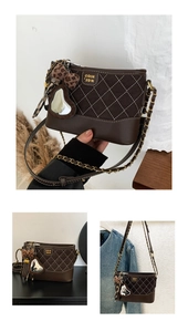 Detail of dark brown quilted crossbody bag with gold chain strap and stylish charms