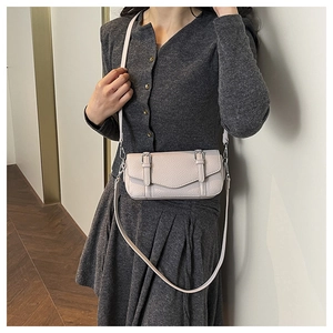 Detail view of cream pebble leather crossbody bag with twin strap buckles on rectangular flap