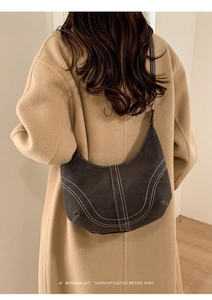 Close-up of retro half-moon shoulder bag with white contrast stitching and matte finish