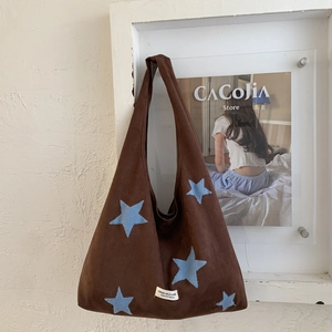 Detail of brown plush tote bag with light blue star embroidery and woven logo patch