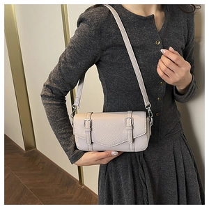 Detail view of the beige lychee pattern messenger bag showing silver buckles and shoulder strap