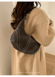 Detail of retro hobo bag with contrast stitching on matte suede texture on a model