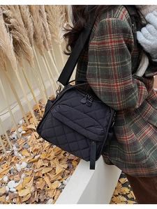 Donna indossa una borsa a tracolla trapuntata nera in nylon in un paesaggio autunnale
