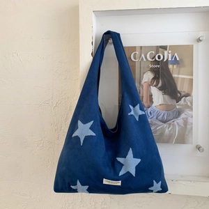 Detailed view of the star embroidery and the branded label on this plush navy blue tote bag