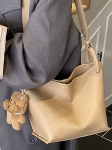 Sac seau beige minimaliste texture litchi avec breloque chiot en peluche pour femme