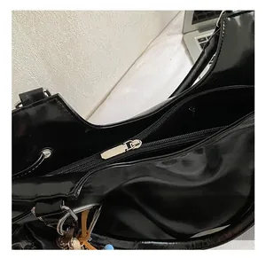 Détails du sac à bandoulière en cuir verni noir brillant avec fermeture éclair et boucle en D