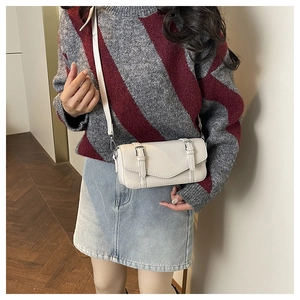 Detail of white lychee pattern faux leather crossbody bag with double buckle straps