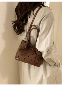 Vue détaillée d'un sac à bandoulière en tweed marron à pois avec nœud et finitions cuir
