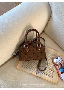 Retro bow-knot pattern Boston bag on open book showing woven texture and leather handles